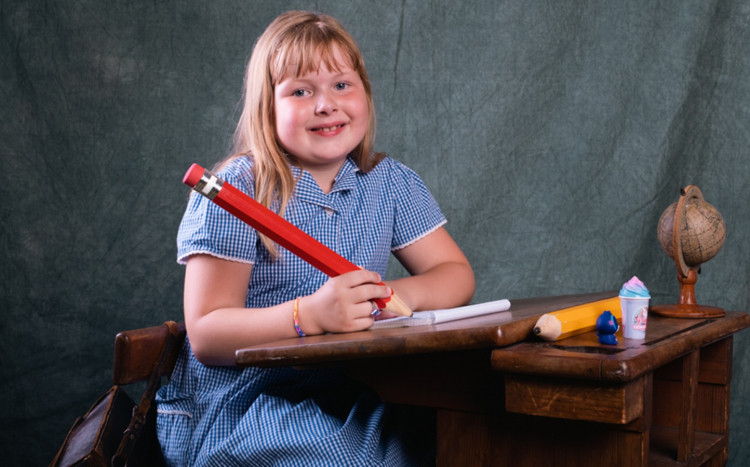 dziewczynka uśmiecha się trzymają duży ołówek