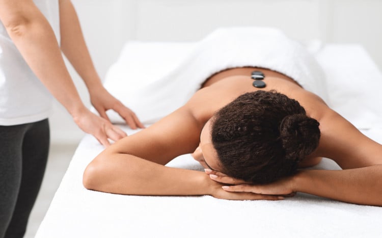 kobieta leżąca na łóżku do masażu