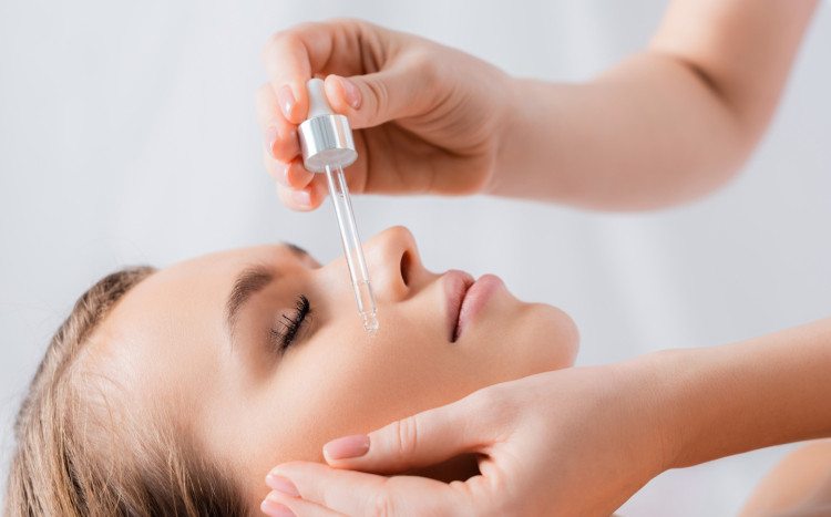 kosmetolog nakłada na twarz kobiety serum
