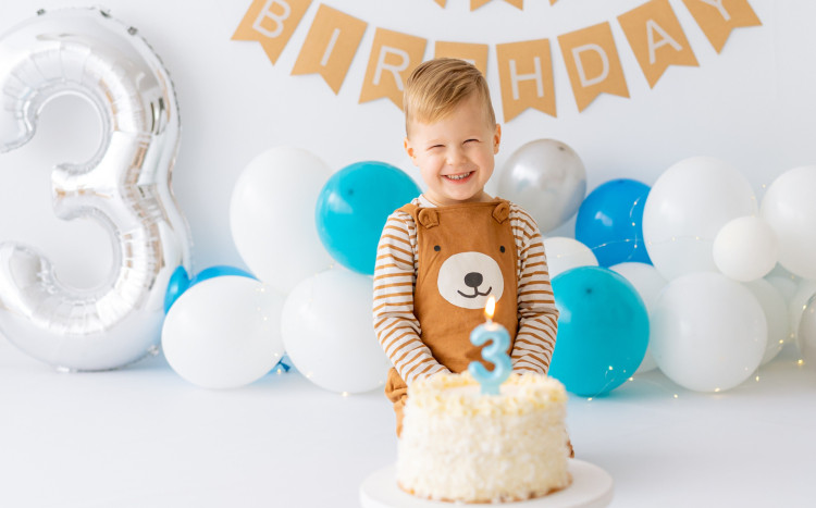 3 letni chłopiec pozuje z dużym tortem urodzinowym