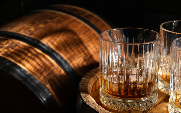 rum w kryształowej szklance i drewniana beczka