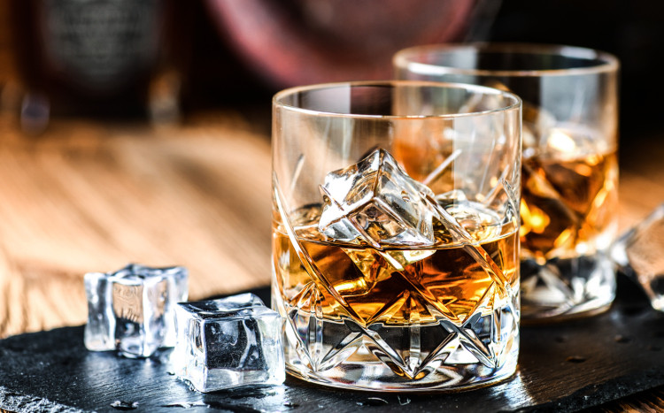 whisky w kryształowej szklance i kostki lodu położone na stole