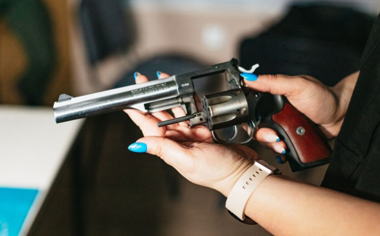 kobieta trzyma w rękach pistolet