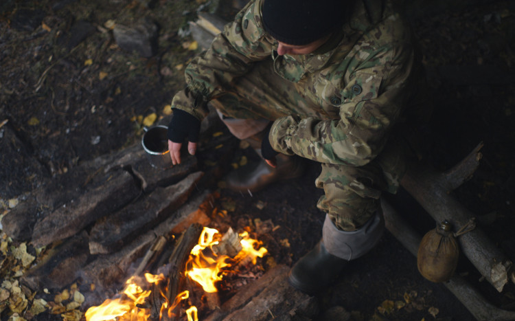 mężczyzna przygotowuje jedzenie przy ognisku po zmroku