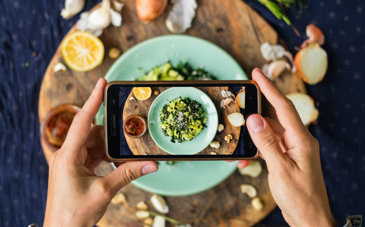 Zbliżenie na smartfon, którym wykonywane jest zdjęcie kolorowego posiłku na talerzu