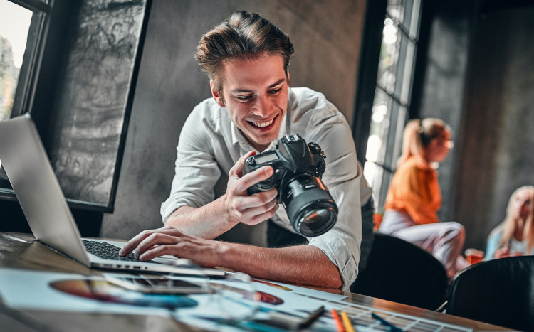 Zadowolony mężczyzna przeglądający zdjęcia w swoim profesjonalnym aparacie
