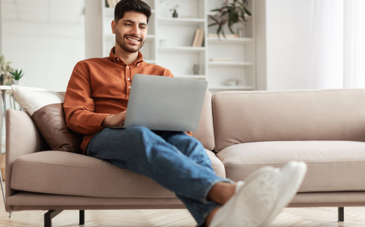 Mężczyzna siedzący na kanapie z laptopem