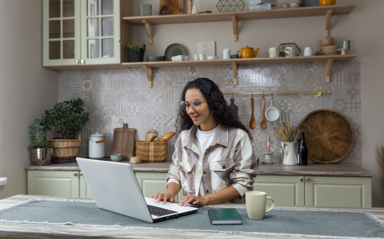 Kobieta siedzi w kuchni z laptopem