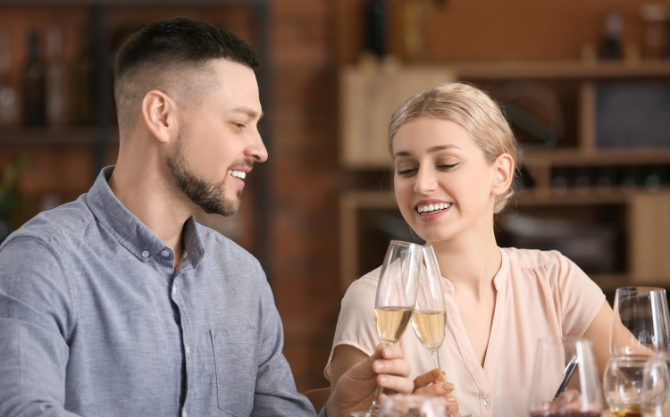 Para uśmiecha się, trzymając kieliszki z szampanem