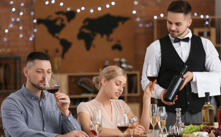 Kelner prezentuje kobiecie i mężczyźnie wino