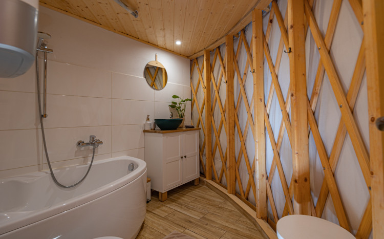 Wnętrze łazienki w jurcie z drewnianym wykończeniem, zlewem, wanną i ubikacją