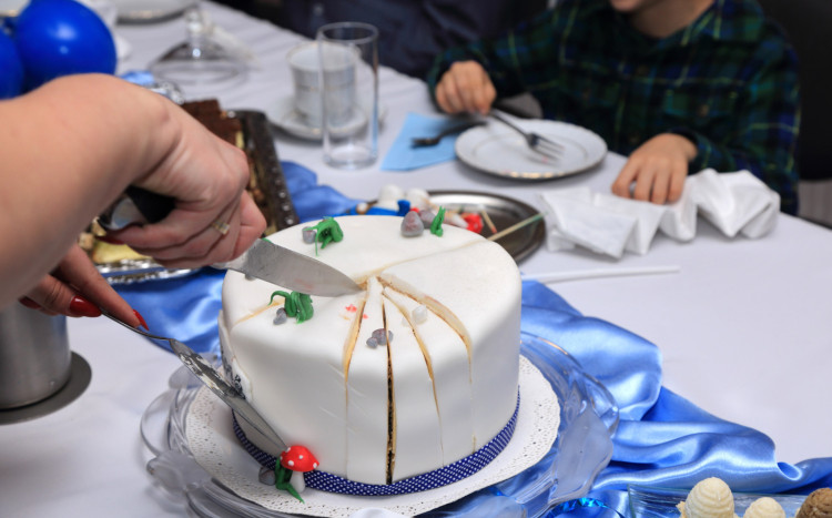 Krojenie urodzinowego tortu w kolorze białym na urodzinach dziecka