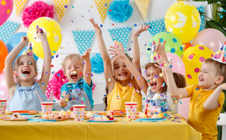 Radosnych pięcioro dzieci podczas urodzin w czapeczkach oraz konfetti dookoła