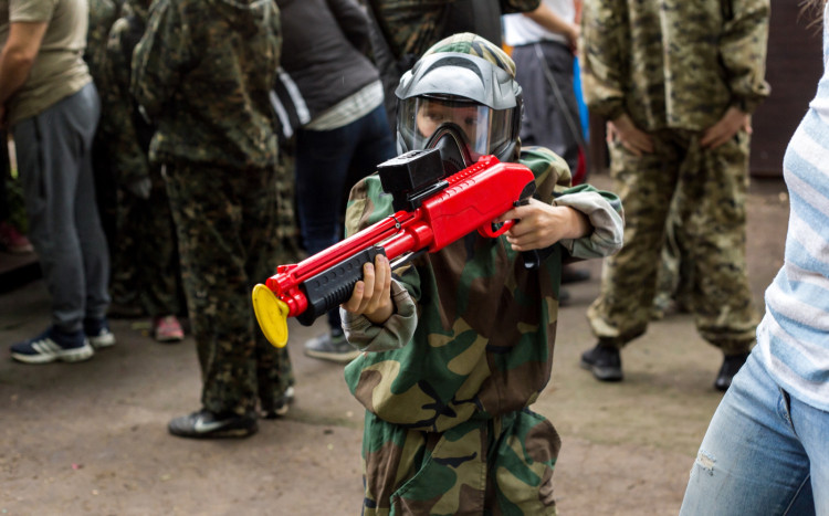 Chłopiec w pełnym ubraniu do paintballu trzymający w ręce i celujący z Jt Splatmaster Shotgun Marker