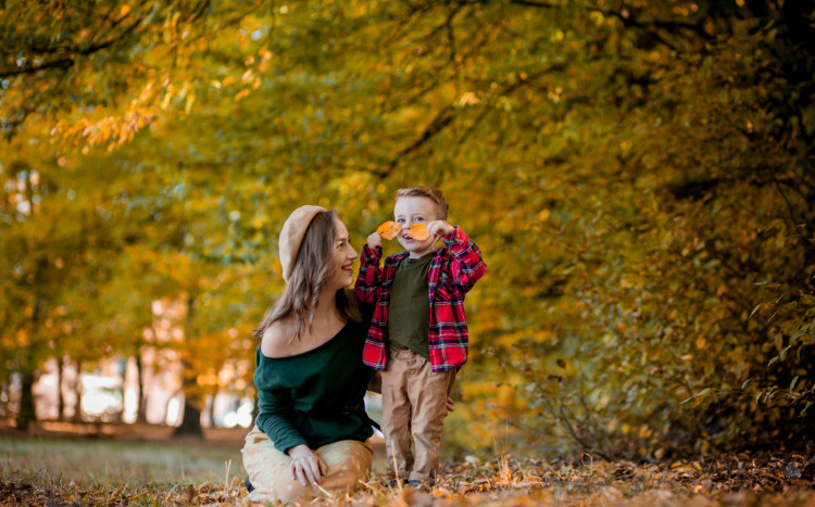 Rodzic z dzieckiem pozuje ze złotymi liśćmi