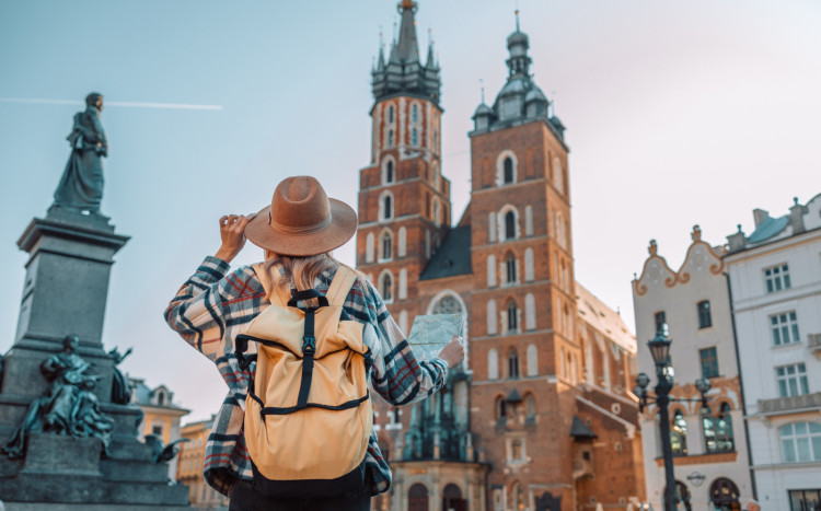 Kobieta w kapeluszu i plecaku patrząca na Kościół Mariacki w Krakowie