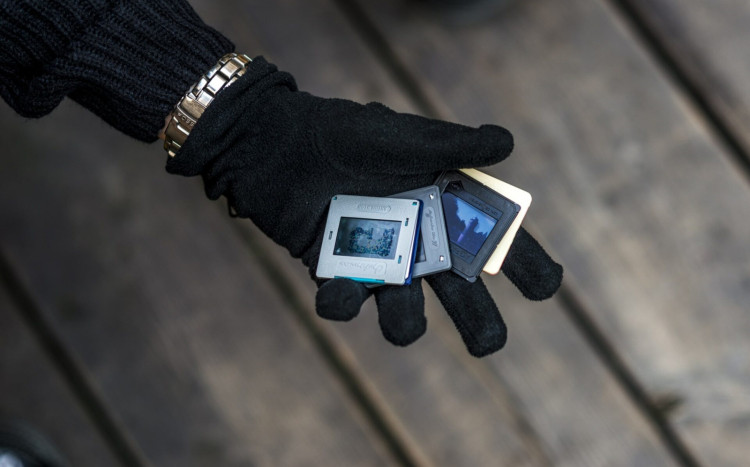 Dłoń w czarnej rękawiczce trzymająca trzy małe kasetki