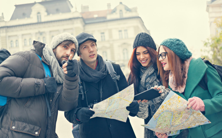 Grup przyjaciół w czapkach z mapami w rękach
