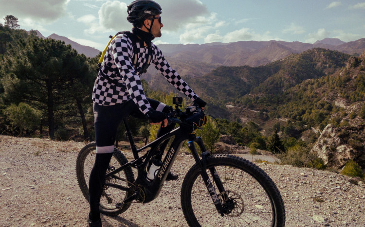 Mężczyzna na rowerze elektrycznym podziwiający góry w Andaluzji