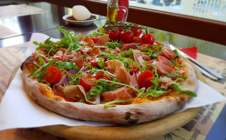Włoska pizza z szynką wolno dojrzewającą, rukolą i pomidorkami