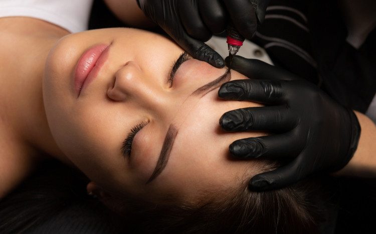 Stylistka wykańcza makijaż brwi w salonie Tattooarnia