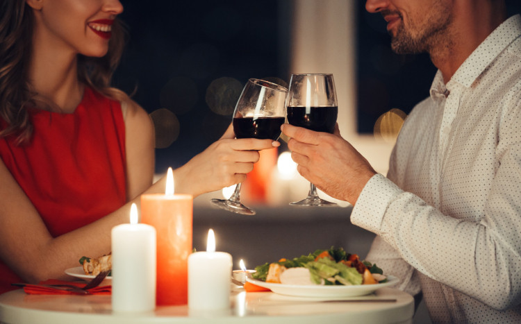 Mężczyzna i kobieta podczas romantycznej kolacji stukający się lampkami z czerwonym winem
