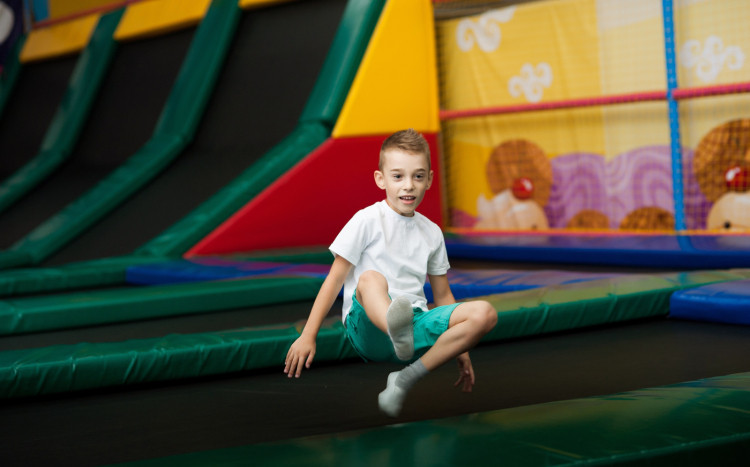 Chłopiec w spodenkach o kolorze morskim skaczący na trampolinie