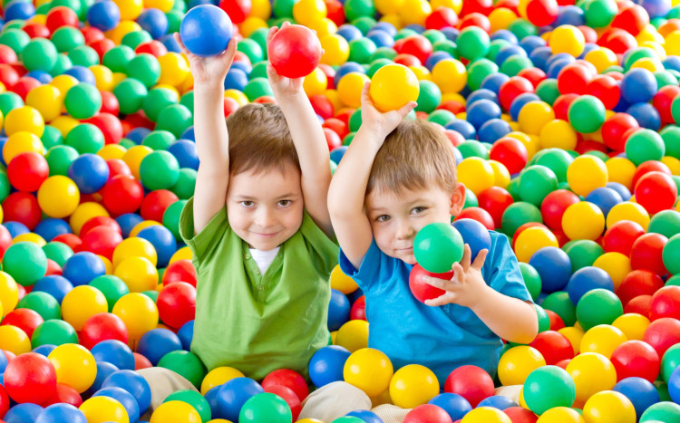 Dwóch chłopców bawiących się w kolorowych kulkach wykonanych z miękkiego plastiku