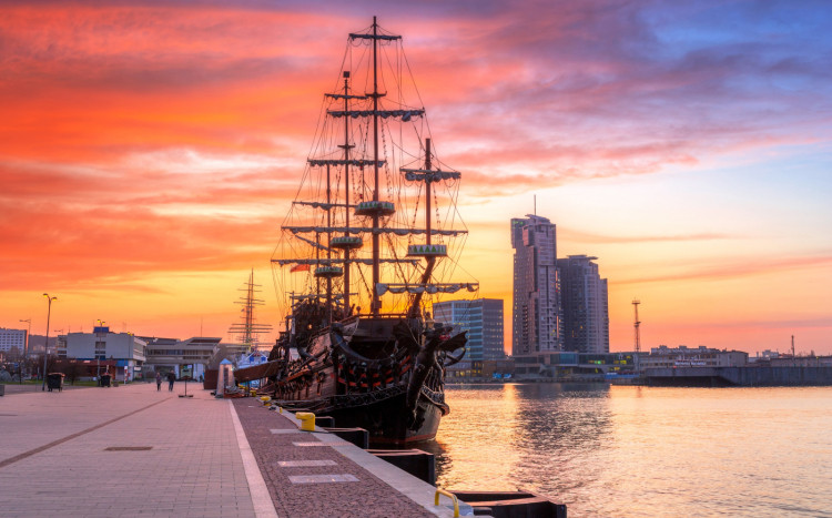 Widok na statek oraz wieżowce w Gdyni o zachodzie słońca