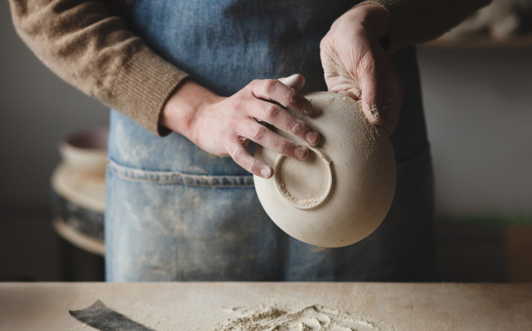 Męskie dłonie tworzące naczynie z gliny