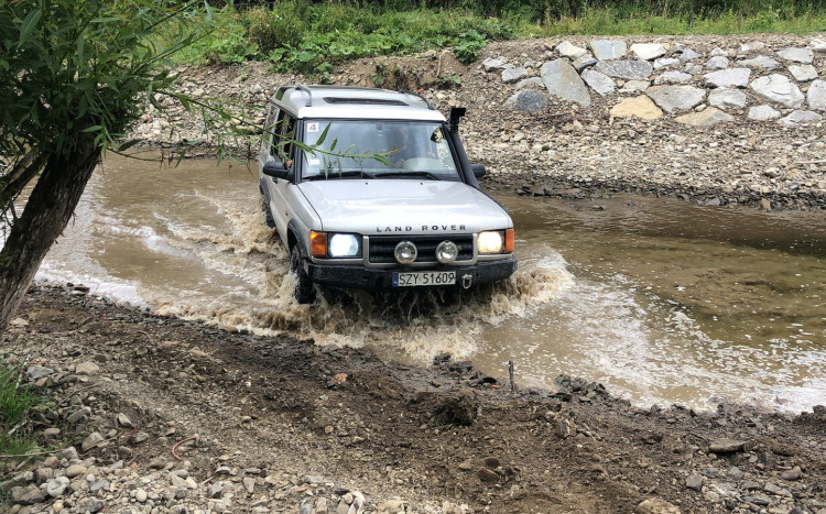Samochód terenowy marki Land Rover przejeżdżający przez rzekę