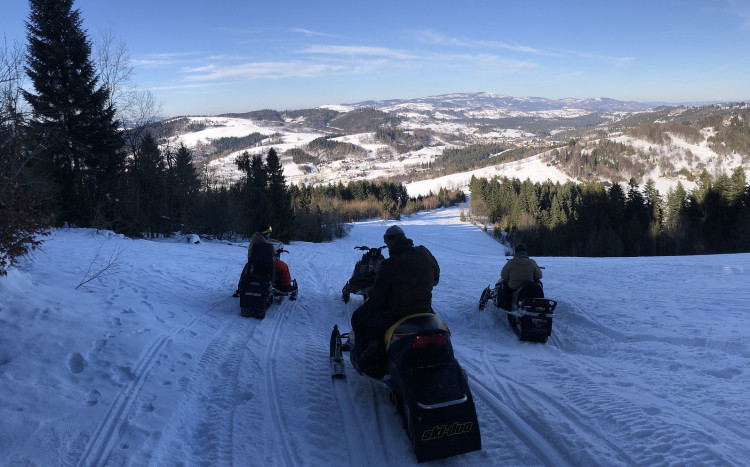 Trzy osoby jadące na skuterze śnieżnym