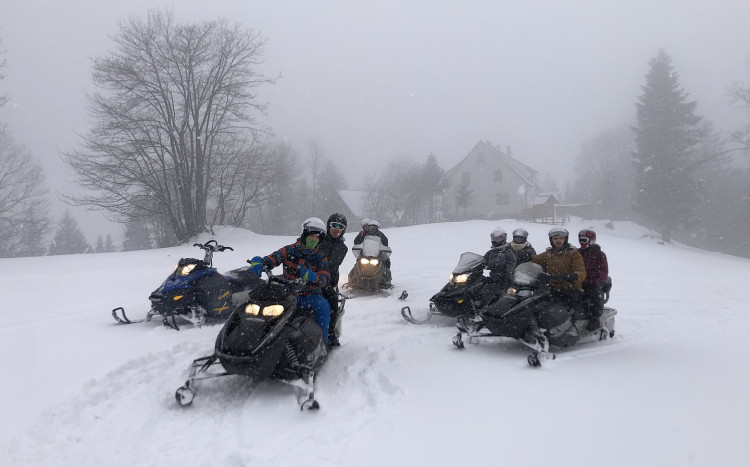Grupa osób wyruszająca na zimową wyprawę skuterami śnieżnymi