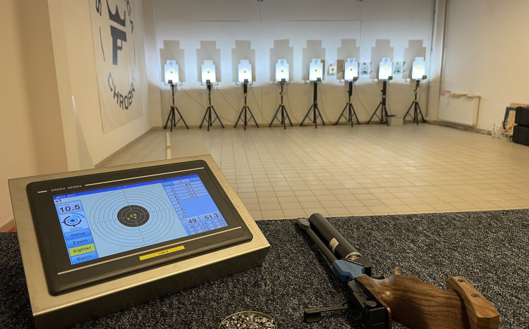 Cele do strzelania, monitor pokazujący cele oraz broń leżąca na stole