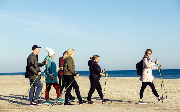 6 szczęśliwych osób podczas spaceru z kijkami nordic walking nad morzem