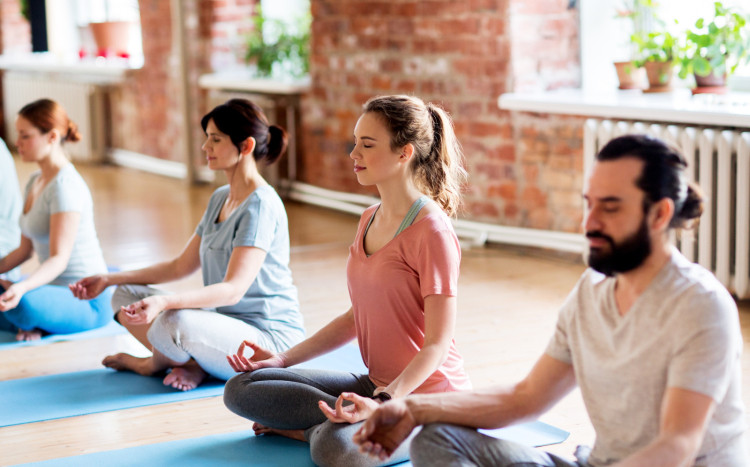 Cztery osoby na niebieskich matach praktykują jogę z medytacją