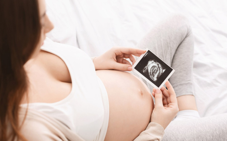 kobieta w ciąży trzyma zdjęcia z usg