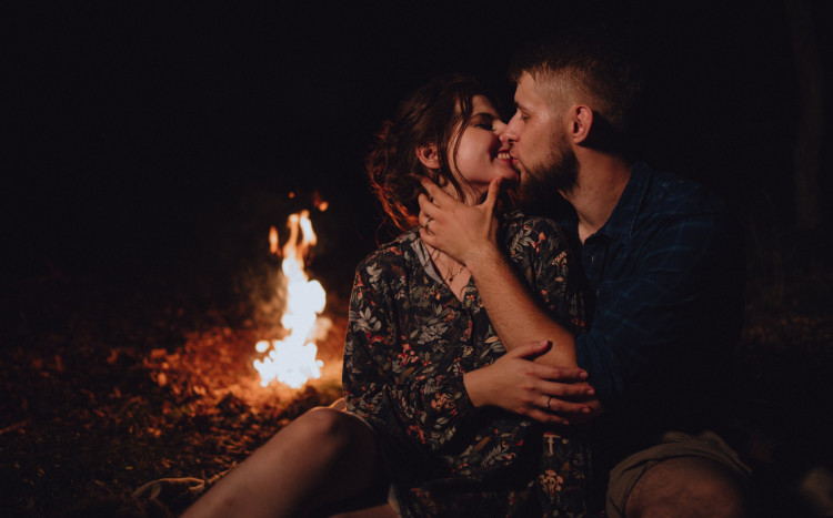 Zakochani ludzie pozujący do zdjęcia nocą przy ognisku
