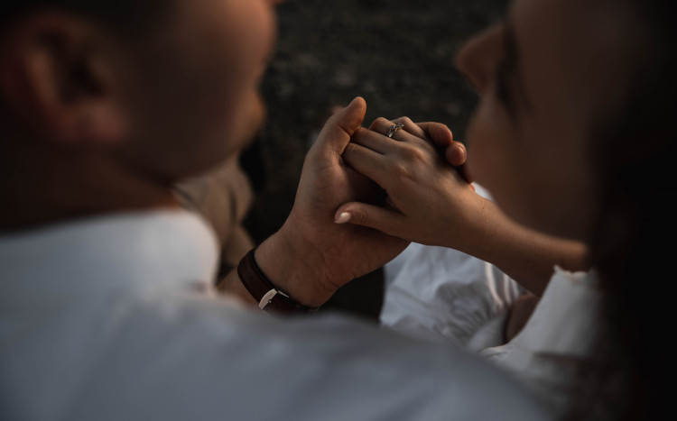 Męska dłoń trzyma kobiecą dłoń, na której widnieje pierścionek zaręczynowy