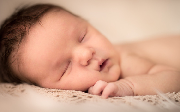 Zdjęcie śpiącego noworodka w ciemnych włosach