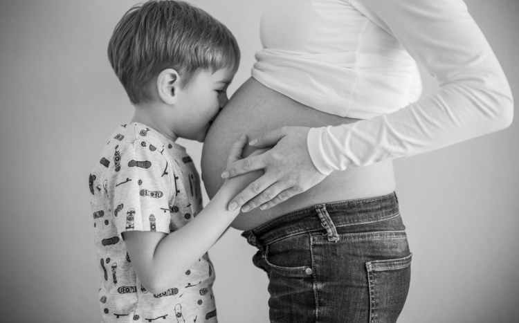 Chłopiec całujący brzuch swojej mamy, która jest w ciąży