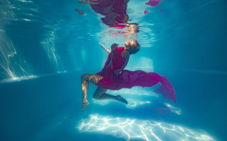 Kobieta w fioletowym ubraniu pozująca do zdjęcia pod wodą
