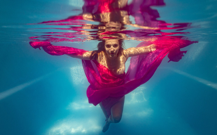 Kobieta w różowej sukience pozująca do zdjęcia pod wodą w basenie