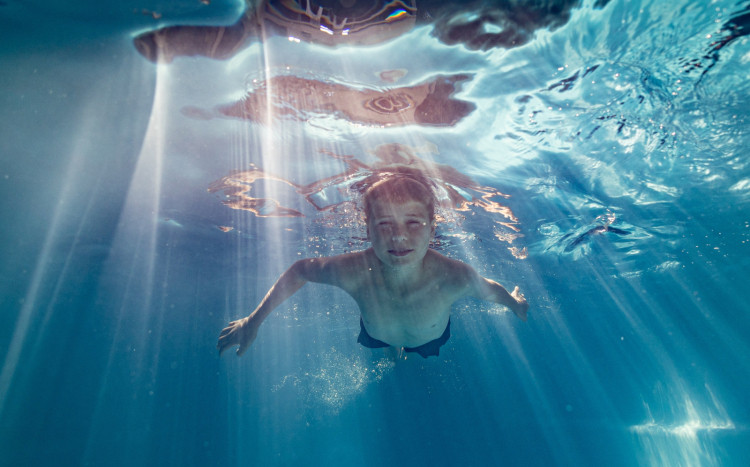 Chłopiec nurkujący pod wodą próbujący otworzyć oczy