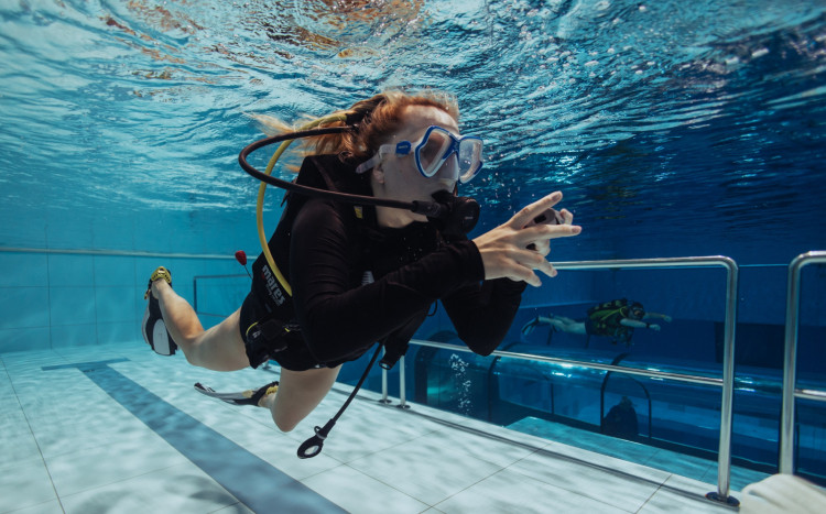 Kobieta w masce tlenowej płynąca pod wodą w basenie