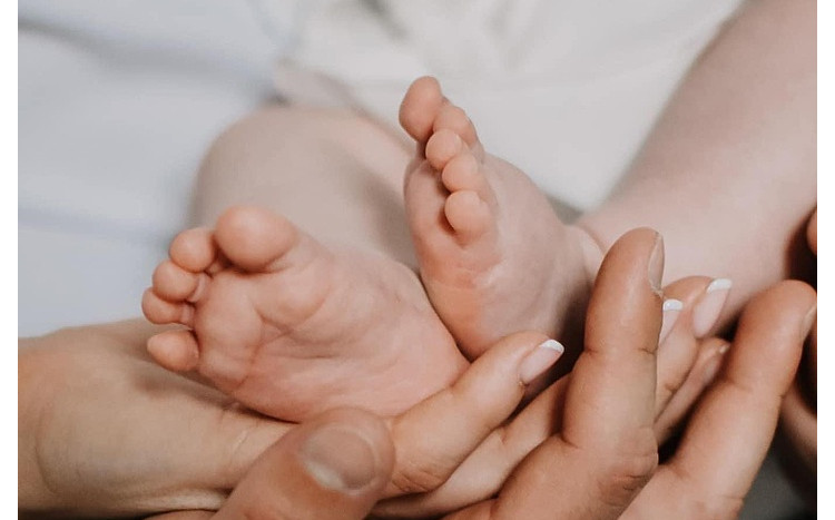Dłonie trzymające małe stópki noworodka