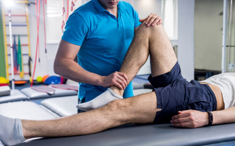 Fizjoterapeuta trzymający stopę i kolano mężczyzny