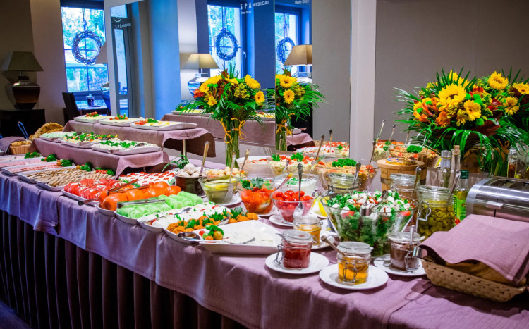 Stół śniadaniowy w formie bufety szwedzkiego pełen warzyw i kolorowych kwiatów