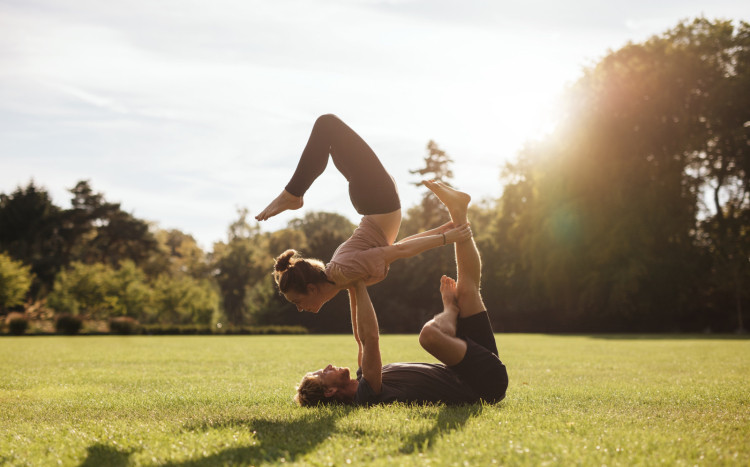 Para ćwicząca na zielonej trawie wspólne pozycje jogi