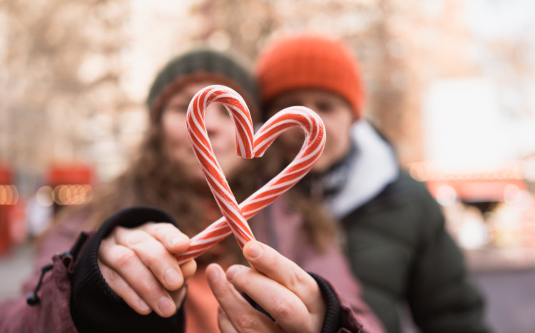Zakochana para tworząca serce z czerwono-białych lasek świątecznych